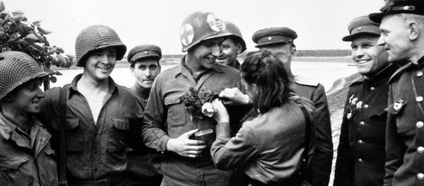 25 апреля 1945 года недалеко от города Торгау на Эльбе войска 1-го Украинского фронта встретились с войсками 1-й армии США. Советская медсестра Любовь Казиченко дарит цветы американскому солдату Карлу Робинсону. 25 апреля 1945 года недалеко от города Торгау на Эльбе войска 1-го Украинского фронта встретились с войсками 1-й армии США. Советская медсестра Любовь Казиченко дарит цветы американскому солдату Карлу Робинсону. - Sputnik Latvija