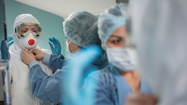 Медицинские работники надевают защитные костюмы и маски для работы с больными с коронавирусной инфекцией - Sputnik Latvija