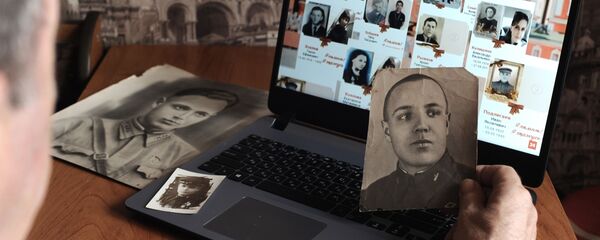 Мужчина смотрит онлайн-трансляцию акции Бессмертный полк - Sputnik Латвия