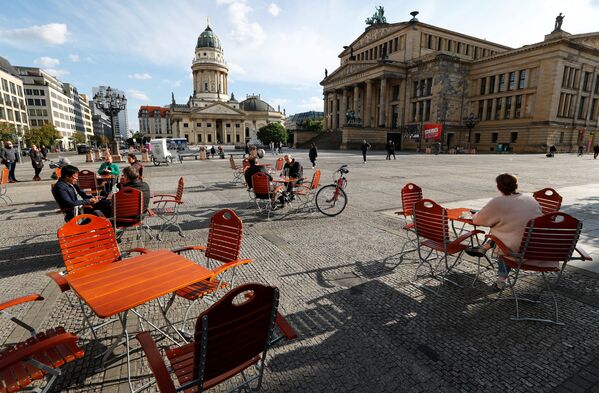 Люди наслаждаются погодой в кафе на площади Жандарменмаркт в Берлине, соблюдая принцип социальной дистанции - Sputnik Латвия