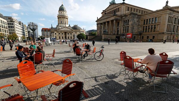 Люди наслаждаются погодой в кафе на площади Жандарменмаркт в Берлине, соблюдая принцип социальной дистанции - Sputnik Латвия