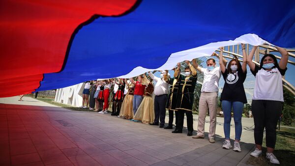 Участники празднований Дня России держат российский флаг в парке Дружбы города Георгиевска Ставропольского края - Sputnik Латвия