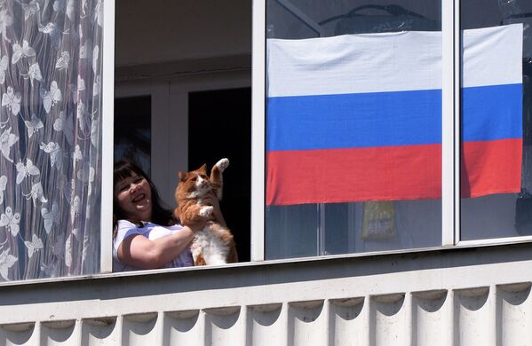 Жительница Красноярска смотрит выступление музыкального ансамбля в День России из окна своей квартиры - Sputnik Латвия