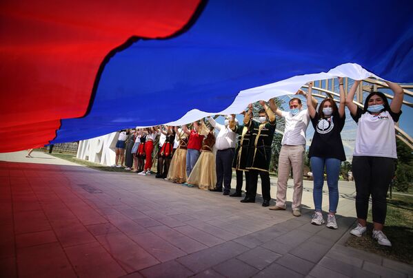 Участники празднований Дня России держат российский флаг в парке Дружбы города Георгиевска Ставропольского края - Sputnik Латвия