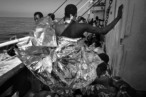 Спасенные мигранты в термоодеялах на борту Маре Джонио из серии итальянского фотографа Франческо Беллина - Sputnik Латвия