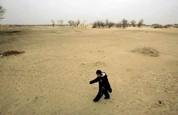 Ребенок идет по песчаной дюне в Вайси, китайская провинция Ганьсу, где нерациональное земледелие привело к опустыниванию - Sputnik Латвия