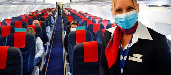 Стюардесса в медицинской маске в салоне самолета в международном аэропорту Брюсселя - Sputnik Латвия