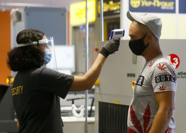 Пассажир в защитной маске проходит температурный контроль в международном аэропорту Борисполь в Киеве - Sputnik Латвия