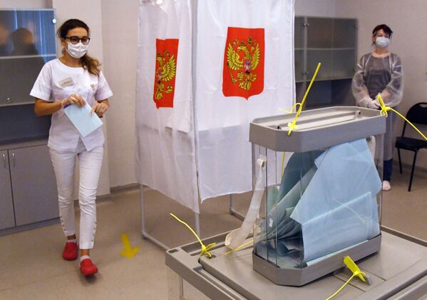 Медицинский работник принимает участие в голосовании по внесению поправок в Конституцию РФ на избирательном участке в Приморском краевом перинатальном центре во Владивостоке - Sputnik Латвия