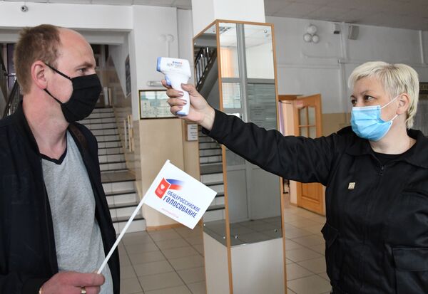 Измерение температуры участника голосования по внесению поправок в Конституцию РФ на избирательном участке №209 в Чите - Sputnik Латвия