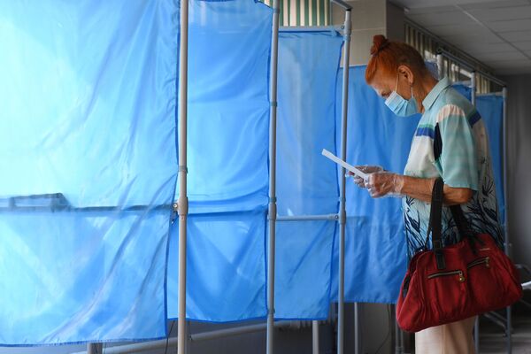 Женщина принимает участие в голосовании по внесению поправок в Конституцию РФ на избирательном участке №1503 в Новосибирске - Sputnik Латвия