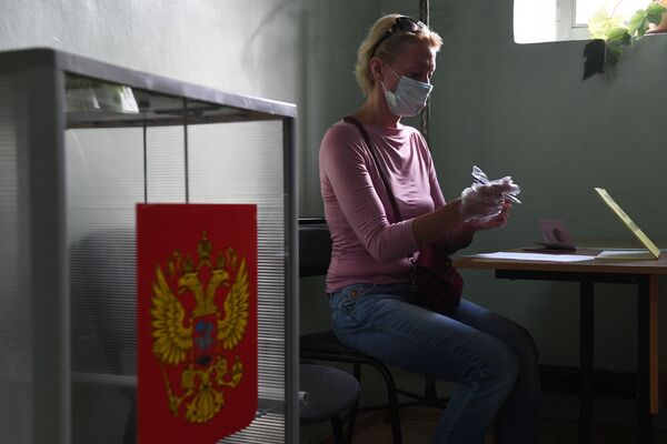 Женщина принимает участие в голосовании по внесению поправок в Конституцию РФ на избирательном участке №1503 в Новосибирске - Sputnik Латвия