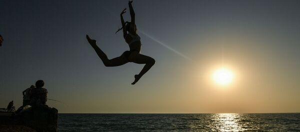 Девушка во время прыжка с пирса на пляже в посёлке городского типа Новофёдоровка Сакского района - Sputnik Latvija