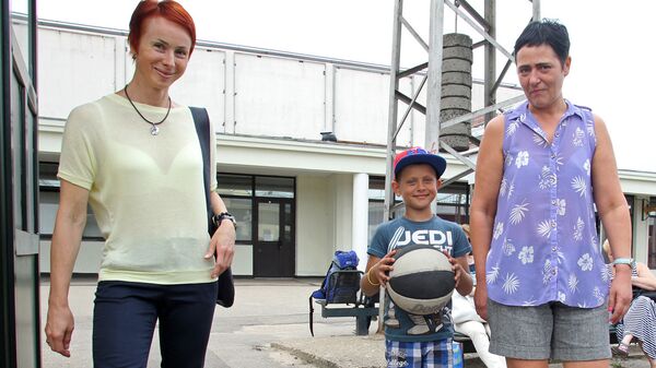 Слева направо: организатор поездки латвийской делегации Байба Зариня, маленький футболист Эмиль и его мама - Sputnik Латвия