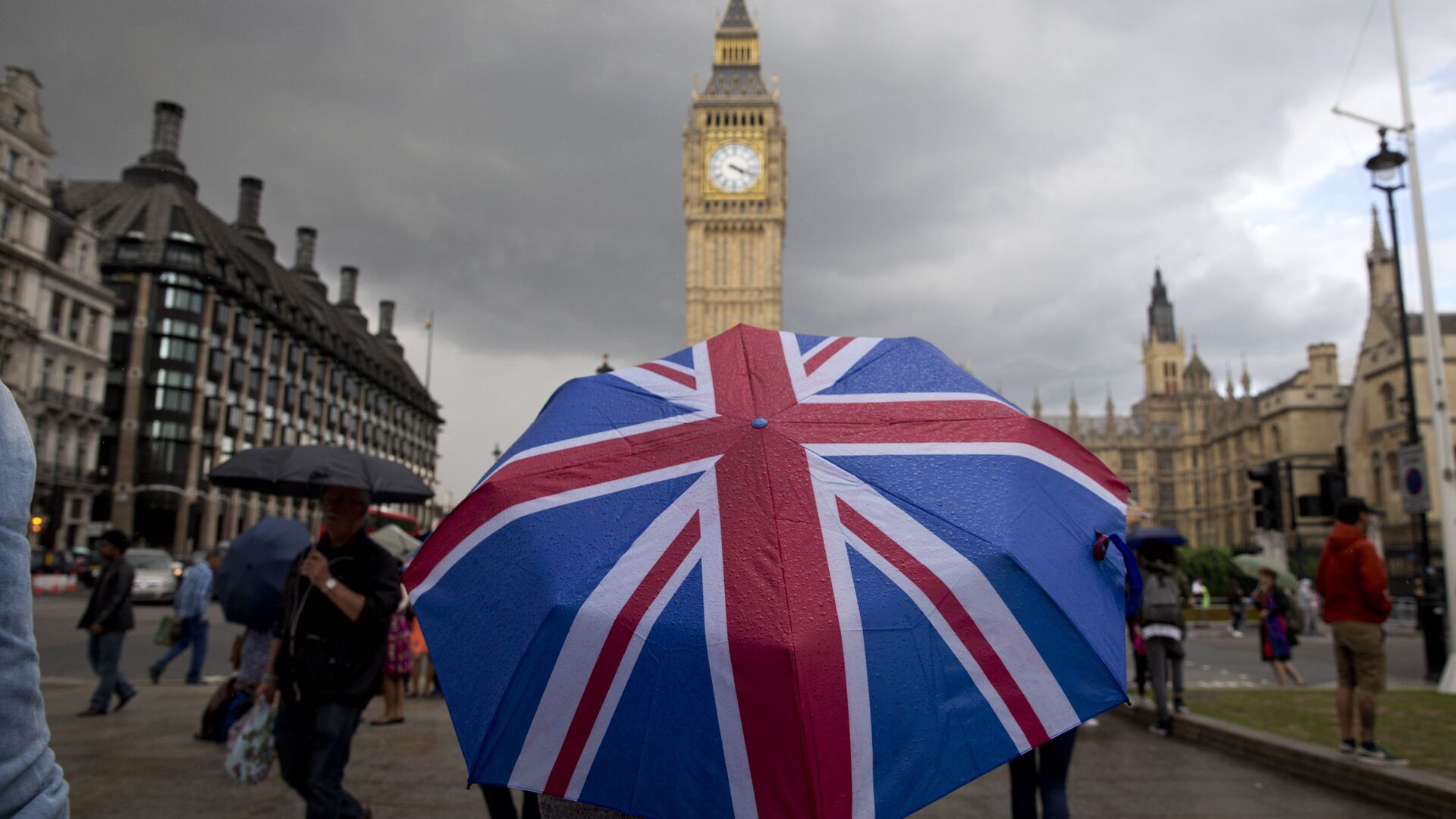 Пешеход с зонтом в цветах британского флага в Лондоне - Sputnik Латвия, 1920, 26.09.2021