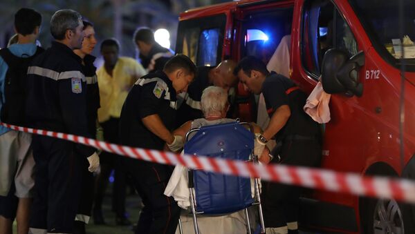 Rescue workers help an injured woman to get in a ambulance on July 15, 2016, after a truck drove into a crowd watching a fireworks display in the French Riviera town of Nice. - Sputnik Latvija