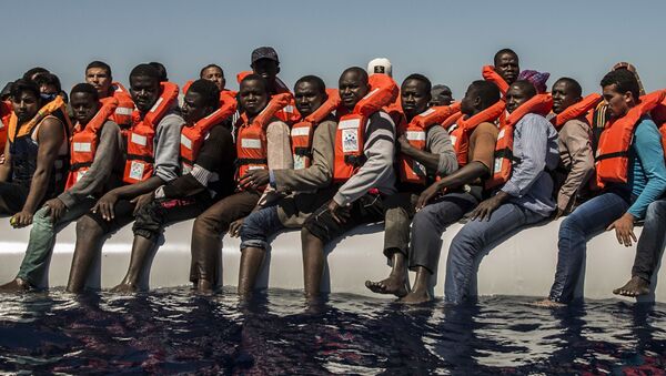 Беженцы ждут спасательную шлюпку в Средиземном море - Sputnik Latvija