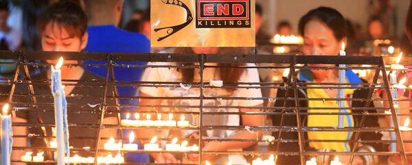 В церкви Редемптористов в Параньяке люди зажигают свечи в память убитых в ходе операции по борьбе с наркотиками В церкви Редемптористов в Параньяке люди зажигают свечи в память убитых в ходе операции по борьбе с наркотиками - Sputnik Латвия