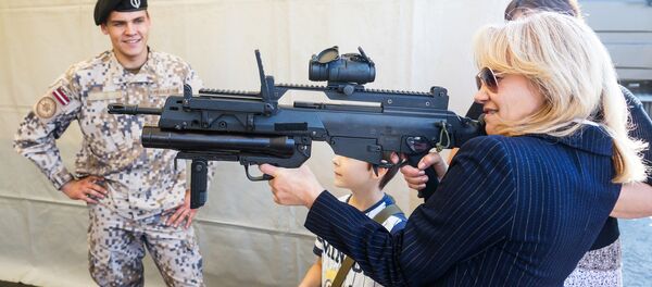 Rīgas iedzīvotāja ar Latvijas Bruņoto spēku standarta šauteni Heckler-Koch G36 Rīgas iedzīvotāja ar Latvijas Bruņoto spēku standarta šauteni Heckler-Koch G36 - Sputnik Latvija