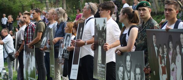 Фотографии в руках потомков на месте расстрела евреев в Молетай - Sputnik Латвия