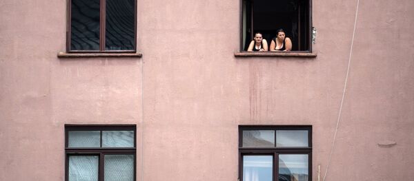Девушки выглядывают в окно одного из домов в старой части города Риги в Латвии - Sputnik Латвия