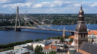 Колокольня Домского кафедрального собора (слева) и вантовый мост через реку Даугаву в Риге в Латвии