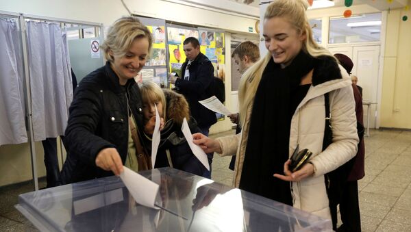 Люди опускают бюллетени в урну на выборах в Вильнюсе, Литва - Sputnik Латвия