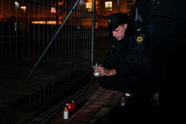 Представитель пожарно-спасательной службы зажигает свечу в память о погибших коллегах - Sputnik Латвия