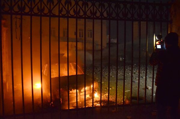 Оператор одного из грузинских телеканалов снимает сожженную в ходе беспорядков в Батуми машину - Sputnik Латвия