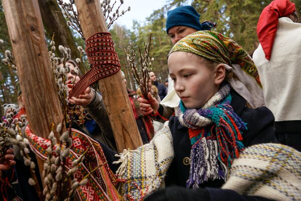 Девочка в нацинальном костюме украшает качели веточками вербы - Sputnik Латвия