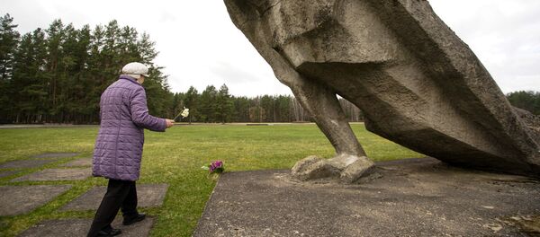 Sieviete noliek ziedus pie figūras Nesalauztais Salaspils Memoriālajā kompleksā Sieviete noliek ziedus pie figūras Nesalauztais Salaspils Memoriālajā kompleksā - Sputnik Latvija