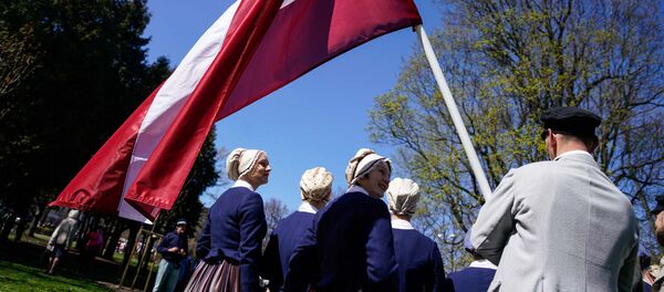 Latviešu tautas kostīmos tērpti mākslinieki ar valsts karogu Latviešu tautas kostīmos tērpti mākslinieki ar valsts karogu - Sputnik Latvija