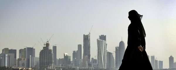 Катарская женщина идет на фоне города Доха - Sputnik Latvija