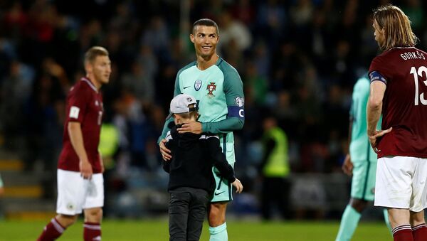 Криштиану Роналду обнимает мальчика, который выбежал на поле во время футбольного матча Португалия - Латвия - Sputnik Латвия