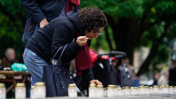 Женщина зажигает поминальную свечу у мемориала Рижской хоральной синагоги - Sputnik Латвия