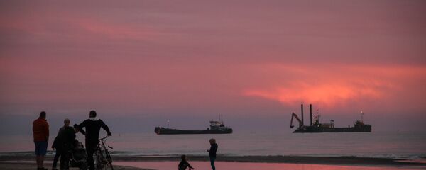 Закат на пляже в Павилосте, на фоне - рыбацкие суда и отдыхающие Закат на пляже в Павилосте, на фоне - рыбацкие суда и отдыхающие - Sputnik Латвия
