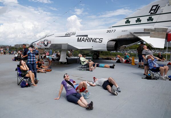 Люди наблюдают солнечное затмение с палубы авианосца Военно-морского музея, корабля ВМС США Йорктаун в Маунт-Плезант, Южная Каролина - Sputnik Латвия