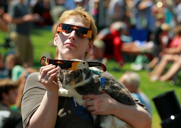 Джейн Уоттс из Хопкинсвилль, Кентукки, наблюдает солнечное затмение с котом в центре города Хопкинсвилл в США - Sputnik Латвия