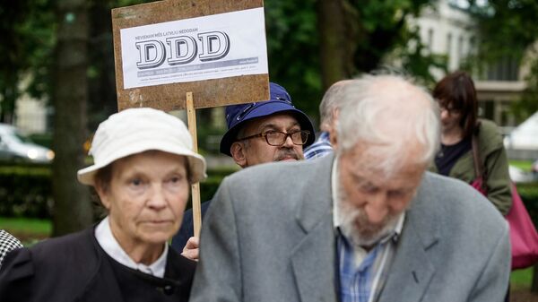 Мужчина с плакатом латышской газеты DDD - декоммунизация, деколонизация, дебольшевизация - Sputnik Латвия