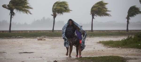Женщина с ребенком защищаются одеялом от дождя и ветра в Кайбариене, Куба - Sputnik Латвия