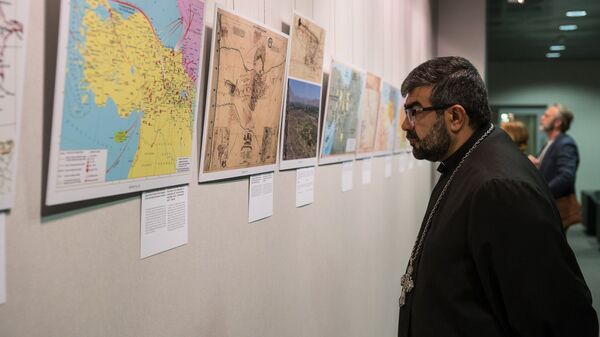 Настоятель Армянской апостольской церкви в Риге преподобный отец Хосров изучает материалы выставки - Sputnik Латвия