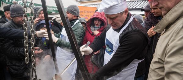 Председатель Комитета городского развития Рижской думы Максим Толстой угощает посетителей праздника душистой ухой Председатель Комитета городского развития Рижской думы Максим Толстой угощает посетителей праздника душистой ухой - Sputnik Латвия