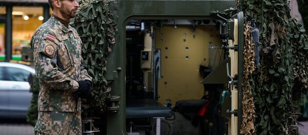 Латвийский военный у латвийского бронетранспортера CVRT Латвийский военный у латвийского бронетранспортера CVRT - Sputnik Latvija