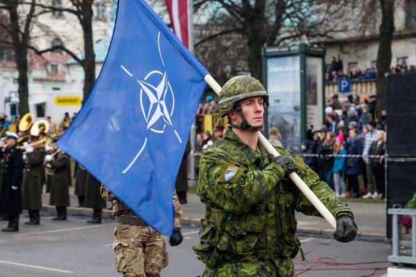 Военнослужащий Канады несет флаг НАТО на военном параде в Риге - Sputnik Латвия