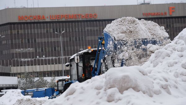 Сотрудник коммунальных служб убирает снег в аэропорту Шереметьево города Москвы - Sputnik Латвия
