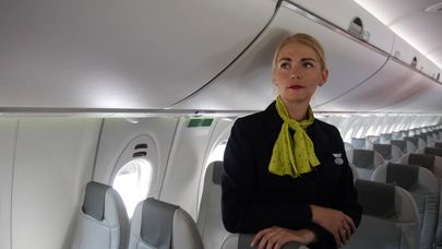 Стюардесса в салоне самолета Bombardier CS300 латвийской авиакомпании airBaltic