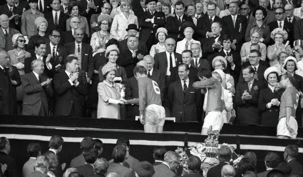 Королева Англии Елизавета II вручает приз VIII первенства мира по футболу Кубок Золотая богиня капитану английской сборной Роберту (Бобби) Муру Королева Англии Елизавета II вручает приз VIII первенства мира по футболу Кубок Золотая богиня капитану английской сборной Роберту (Бобби) Муру - Sputnik Латвия