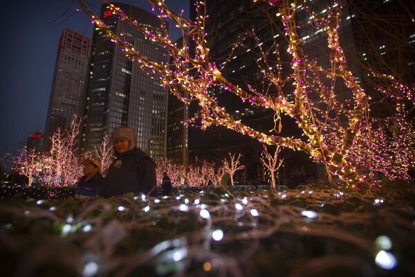 People walk past a display of Christmas lights outside a building in the central business district of Beijing - Sputnik Latvija