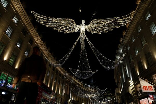 A man walks beneath Christmas street lights on Regent Street in London, Britain - Sputnik Latvija