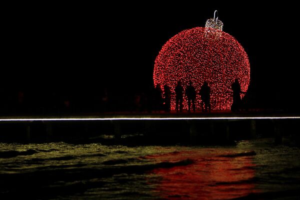 People are silhouetted on a pedestrian dock decorated with an illuminated Christmas ornament in the southern coastal city of Larnaca on the eastern Mediterranean island of Cyprus - Sputnik Latvija